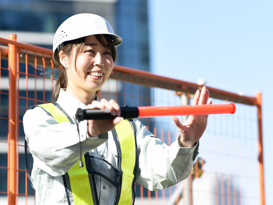 工事現場で誘導棒を掲げる女性警備員